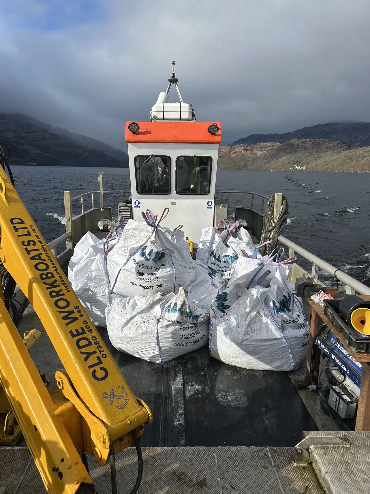 Multicat deck carrying aggregate bags with crane and cabin visible