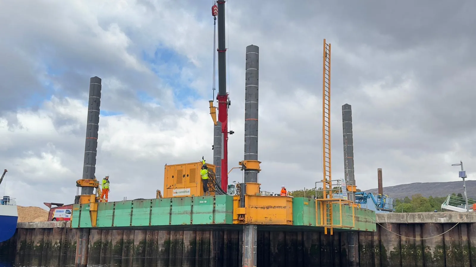 Jack-up platform with a crane and workers beside a quay